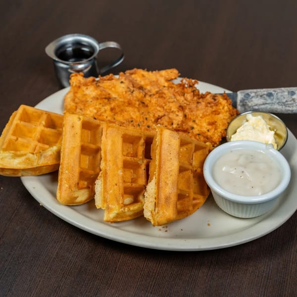 Good Day Cafe's chicken and waffles with gravy, butter, and syrup on a white plate.