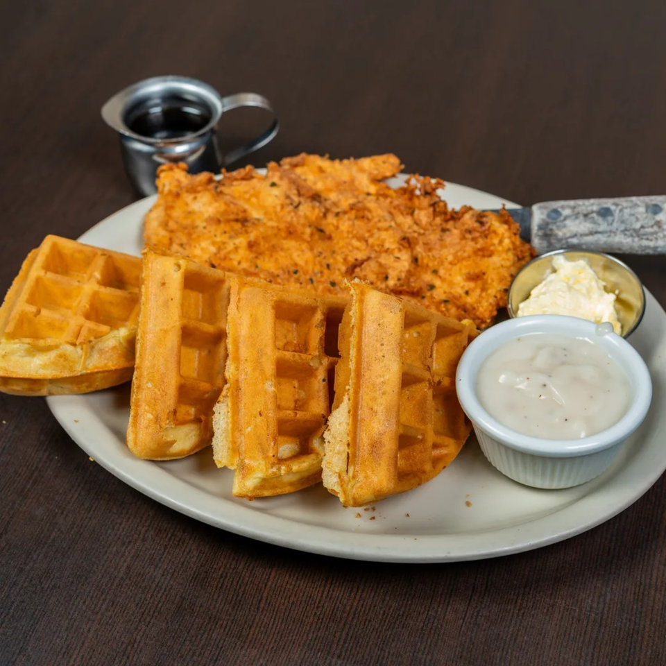 Good Day Cafe's chicken and waffles with gravy, butter, and syrup on a white plate.