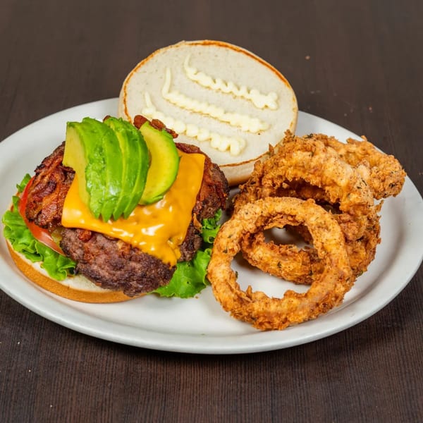 Good Day Cafe's avocado cheeseburger with bacon, lettuce, tomato, and a side of crispy onion rings.